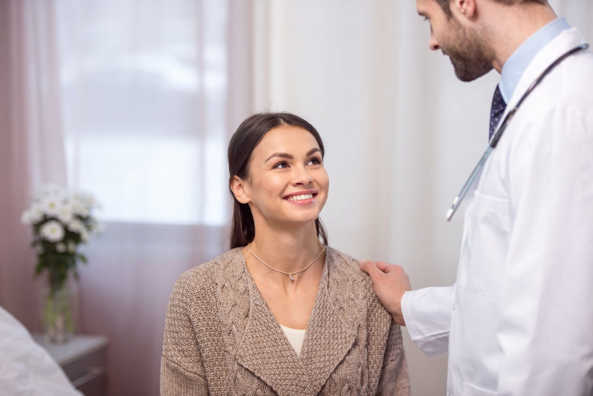 A woman is smiling as a doctor examines her chest