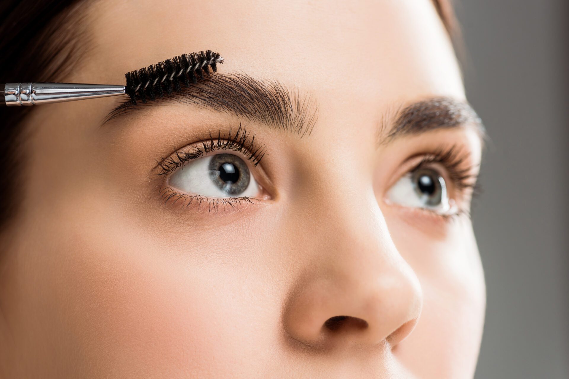 young woman styling eyebrow with eyebrow brush