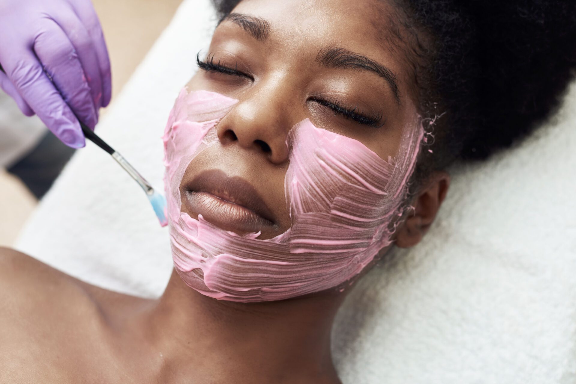 The beautician applies a moisturizing mask to the client's face